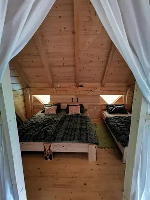 an attic bedroom with two beds in a wooden house at Kamp Beli gaber in Stari Trg pri Ložu