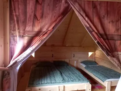 two beds in the attic of a wooden cabin at Kamp Beli gaber in Stari Trg pri Ložu