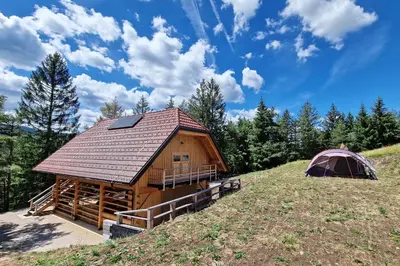 a log cabin and a tent on a hill at Kamp Beli gaber in Stari Trg pri Ložu
