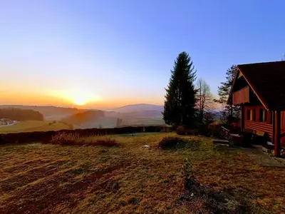 a sunset over a field next to a cabin at Chalet Panorama in Občine