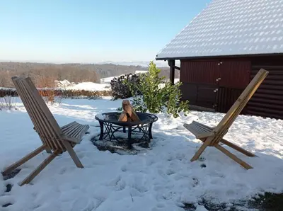 a person sitting in a table in the snow with two chairs at Chalet Panorama in Občine