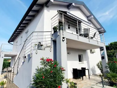a white house with a balcony and flowers at Villa Ines in Zgornje Škofije