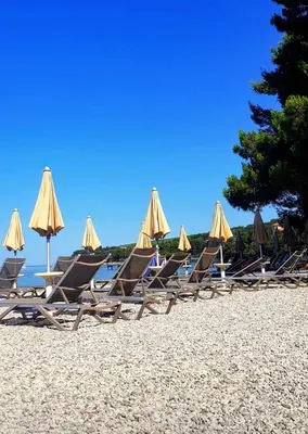a group of lounge chairs and umbrellas on a beach at Villa Ines in Zgornje Škofije