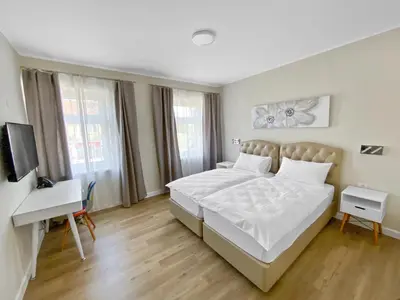 a bedroom with a bed and a desk and a television at TOSCANINA Garni Hotel in Dobrovo