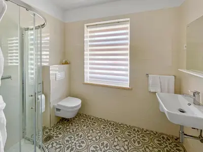 a bathroom with a toilet and a sink and a window at TOSCANINA Garni Hotel in Dobrovo