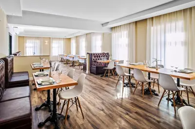 a restaurant with wooden tables and white chairs at TOSCANINA Garni Hotel in Dobrovo