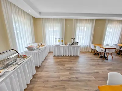 a restaurant with white tables and chairs and windows at TOSCANINA Garni Hotel in Dobrovo