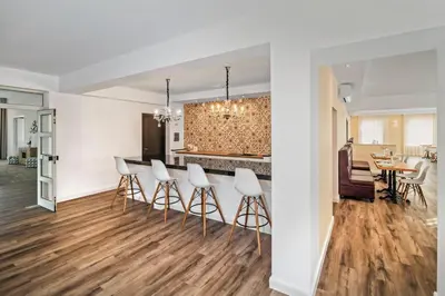 a kitchen and dining room with white walls and wood floors at TOSCANINA Garni Hotel in Dobrovo