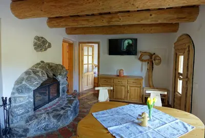 a living room with a table and a stone fireplace at Natur apartma Rudi in Begunje na Gorenjskem