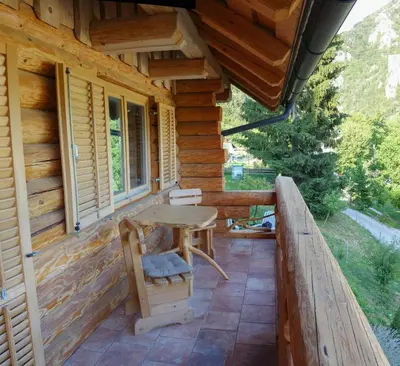 a porch of a log cabin with a table and chairs at Natur apartma Rudi in Begunje na Gorenjskem