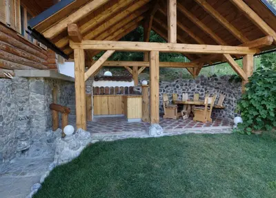 a wooden pavilion with a table and chairs in a yard at Natur apartma Rudi in Begunje na Gorenjskem