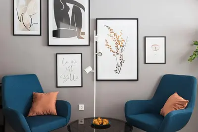two blue chairs and a table in a room with pictures at New Central Studios with parking in Ljubljana
