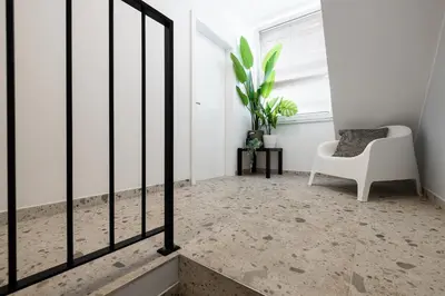 a living room with a white chair and a window at New Central Studios with parking in Ljubljana