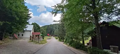 an empty road with trees and a white building at Koča Kresnica in Ilirska Bistrica