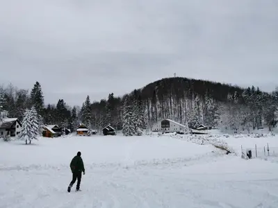 a man is walking through a snow covered field at Koča Kresnica in Ilirska Bistrica