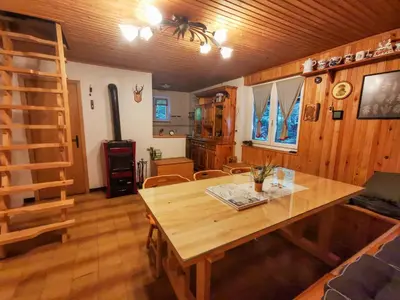 a dining room with a wooden table and a ladder at Koča Kresnica in Ilirska Bistrica