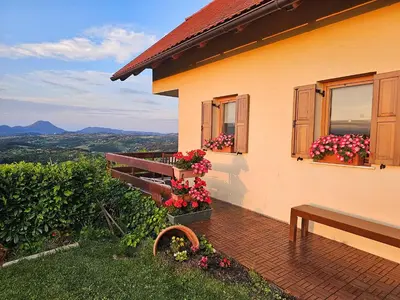 a house with flowers and a bench in front of it at Holiday House PANORAMA in Podčetrtek