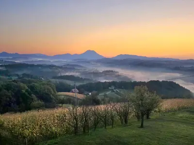 a sunset over a field with mountains in the background at Holiday House PANORAMA in Podčetrtek