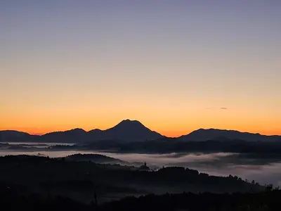 a view of a foggy valley at sunset with mountains at Holiday House PANORAMA in Podčetrtek