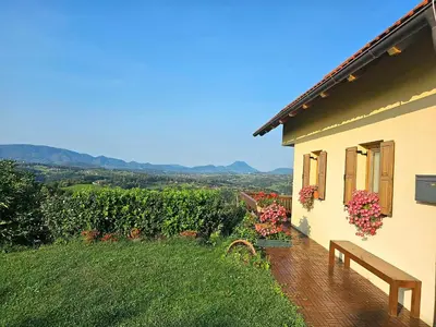 a house with a bench and flowers on the side of it at Holiday House PANORAMA in Podčetrtek