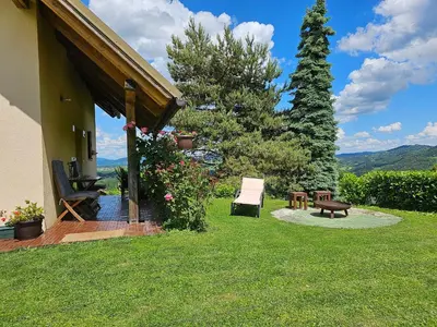 a house with a chair and a bench in the yard at Holiday House PANORAMA in Podčetrtek