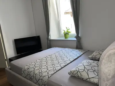 a bedroom with two beds and a television and a window at Ljubljana Studios in Ljubljana