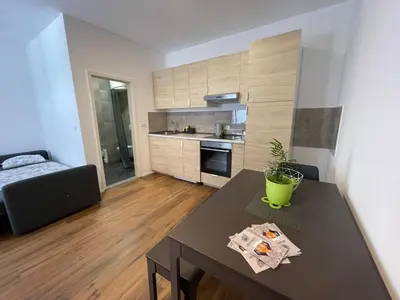 a living room with a table and a kitchen at Ljubljana Studios in Ljubljana
