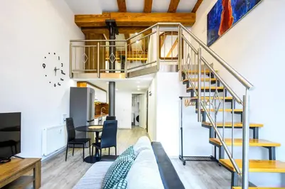 a living room and dining room with a spiral staircase at The Comfortable Loft in Ljubljana