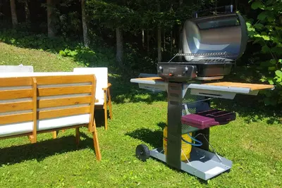 a grill with a television on it next to a bench at Cottage House Jakob in Cerklje na Gorenjskem