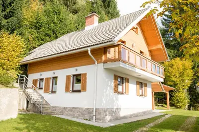 a house with wooden accents and a yard at Cottage House Jakob in Cerklje na Gorenjskem