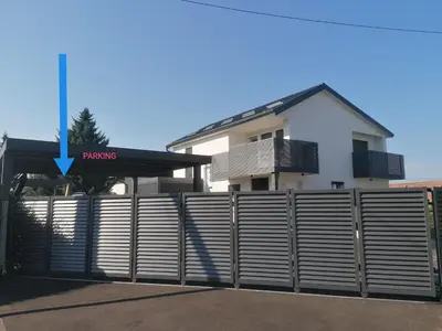 a fence in front of a house with a building at Apartment Sunset in Maribor
