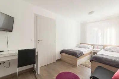 a bedroom with two beds and a desk and a television at Apartments Fine Stay Slovenia in Žirovnica