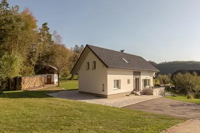 a small white house with a driveway at Apartments Fine Stay Slovenia in Žirovnica