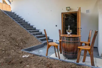 a table and chairs with a wine barrel and stairs at Hiska B&N Podlehnik in Podlehnik