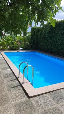 a blue swimming pool with two metal rails in a yard at Apartman MURKO P-2 in Brest
