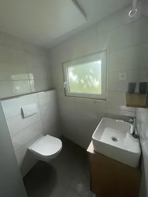 a bathroom with a toilet and a sink and a window at Azimut Hiša in Tolmin