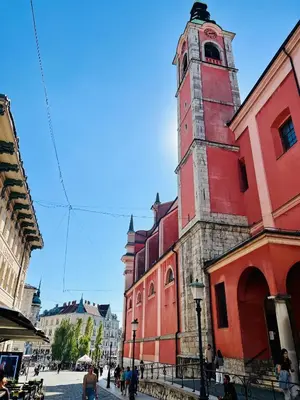 a red building with a clock tower on a street at Galleria apartment Ljubljana in Ljubljana