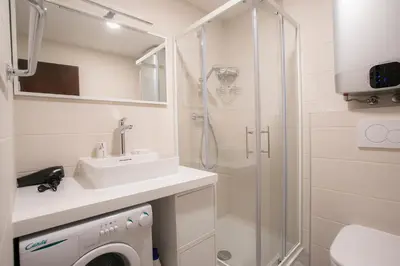 a bathroom with a sink and a shower and a washing machine at Apartment Vera Kranjska Gora in Kranjska Gora