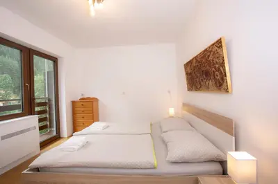 a white bedroom with two beds and a window at Apartment Vera Kranjska Gora in Kranjska Gora