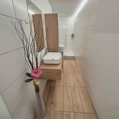 a bathroom with a toilet and a vase with a flower at Annie's apartment in Bled