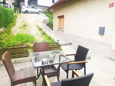 a patio with a glass table and chairs on a patio at Small house in Celje in Celje
