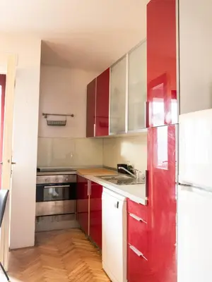 a kitchen with red cabinets and a white refrigerator at Nice family friendly apartment in the city center in Ljubljana