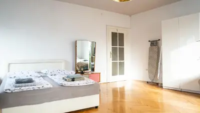 a white bedroom with a bed and a mirror at Nice family friendly apartment in the city center in Ljubljana