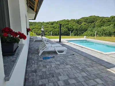 a patio with two lounge chairs next to a swimming pool at Villa Hojnik in Videm pri Ptuju