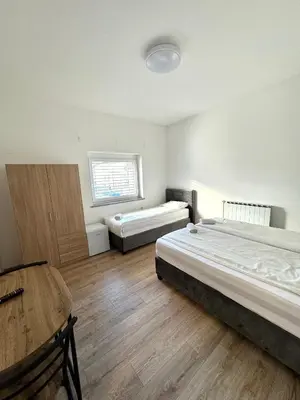 a bedroom with two beds and a table in it at L&L rooms in Maribor