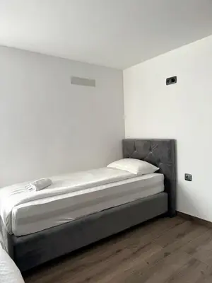 a bed in a room with white walls and wooden floors at L&L rooms in Maribor