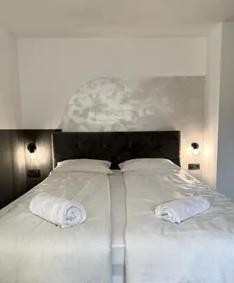 a large white bed with two white towels on it at L&L rooms in Maribor