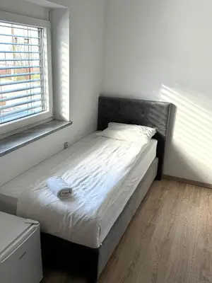 a bed in a white room with a window at L&L rooms in Maribor