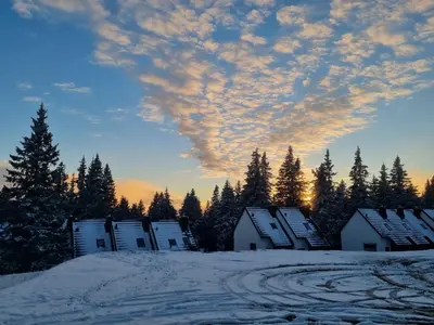 a group of houses in the snow at sunset at Apartment Bajta - Rogla in Zreče