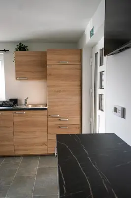 a kitchen with wooden cabinets and a black counter top at Prima Countryside Apartments in Žirovnica